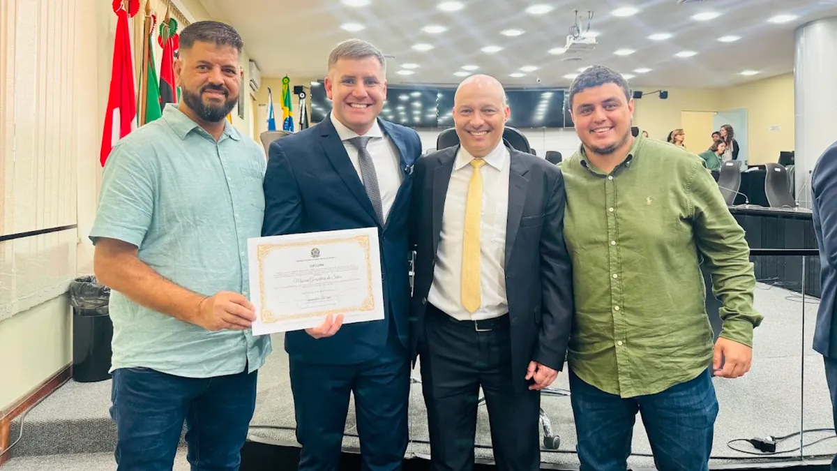 Maicon Gonçalves na Câmara Municipal segurando um documento ao lado de três pessoas